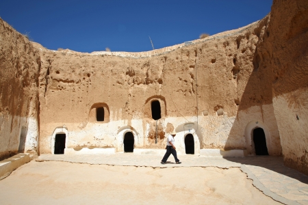 MATMATA, TUNISIA - SEPTEMBER 17  The largest region of the troglodyte communities  One of many dwellings - fragment of courtyard excavated in the rock  circular crater a few meters deep  on September 17, 2012 in Matmata, Tunisia  Inmate in front of his trのeditorial素材
