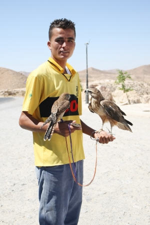 Matmata, Tunisia -  September 17th, 2012    One of the beggars with two hawks holding in his hands on the tourist point in Matmata, Tunisia  Beggars are typical occurrence in Tunisia  Wherever there are tourists and tourist point, beggars come with a variのeditorial素材