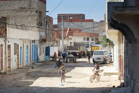 Kairouan, Tunisia -  September 16th, 2012   People on the unpaved and dusty streets in the suburb of Kairouan,  Tunisia  In the suburb, most of residential buildings are unfinished のeditorial素材