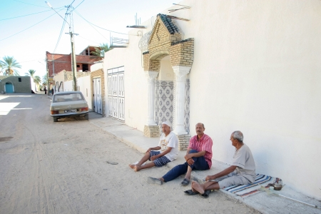 Tozeur, Tunisia -  September 16th, 2012    Three men resting in front of house on the floor of the street, along the tourist route through La Palmerie Oasis in Tozeur, Tunisia  のeditorial素材