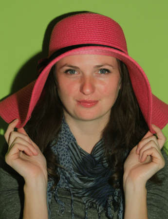 Portrait of a young woman with pinky straw hat  on green background 