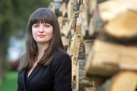 A portrait of a young business woman posing next to stacks of wood and looking at the camera 