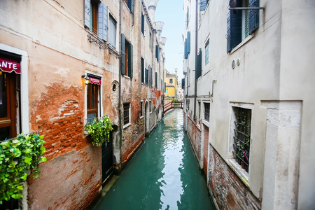 A narrow water canal next to a pizzeria in Venice, Italy.の写真素材