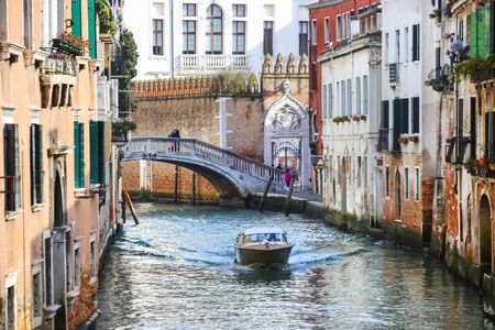 VENICE, ITALY - FEBRUARY 15 :A view of a boat sailing in the water canal with people walking over the bridge on February 15th, 2014 in Venice, Italy.のeditorial素材