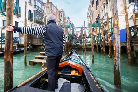 VENICE, ITALY - FEBRUARY 15 :  A rear view of a gondolier parking the gondola at a gondola station in a grand canal on February 15th, 2014 in Venice, Italy.のeditorial素材