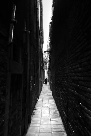 VENICE, ITALY - FEBRUARY 15 : A woman walking in the narrow street between buildings on both sides on February 15th, 2014 in Venice, Italy.のeditorial素材