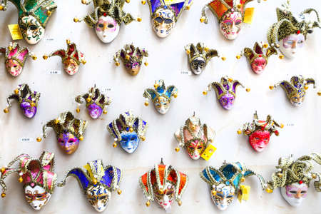 Colorful souvenir carnival masks with magnets displayed for sale on stand in Venice, Italy.の写真素材