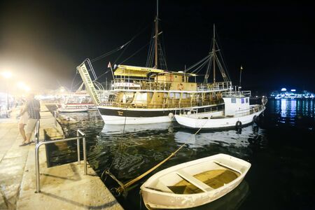 ROVINJ CROATIA  AUGUST 6 : Tourists boats moored in the marina next to people walking on the promenade at night on August 6th 2013 in Rovinj Croatia.のeditorial素材
