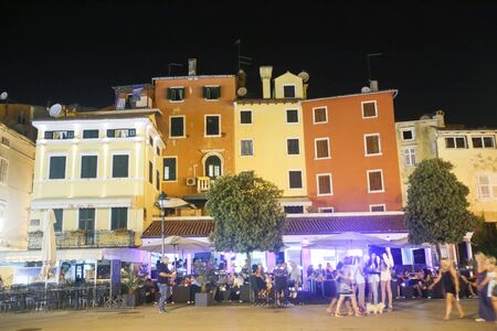ROVINJ CROATIA  AUGUST 6 : Tourists walking on the promenade next to people sitting on a terrace of a night club on August 6th 2013 in Rovinj Croatia. Rovinj is a tourist destination on Adriatic coast of Croatia.のeditorial素材