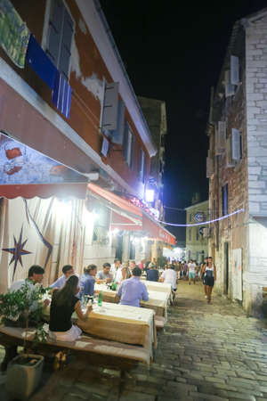 ROVINJ CROATIA  AUGUST 6 : People sitting in a restaurant at night with tourists passing by on August 6th 2013 in Rovinj Croatia. Rovinj is a tourist destination on Adriatic coast of Croatia.のeditorial素材