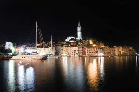 ROVINJ CROATIA  AUGUST 5 : A view of the Saint Eufemia church and bell tower in the old city core and boats moored in the Adriatic sea next to buildings at night on August 5th 2011 in Rovinj Croatia. Rovinj is a tourist destination on Adriatic coast of Crのeditorial素材