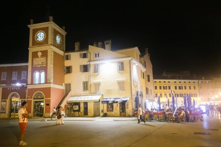 ROVINJ CROATIA  AUGUST 6 : Tourists walking in the street next to people sitting in a restaurant on the promenade on August 6th 2013 in Rovinj Croatia. Rovinj is a tourist destination on Adriatic coast of Croatia.のeditorial素材