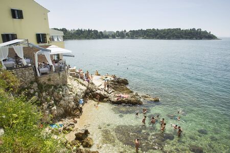 ROVINJ CROATIA  JULY 20 : A high angle view of people swimming and sunbathing on the rocks of the city beach next to a beach restaurant on July 20th 2014 in Rovinj Croatia. Rovinj is a popular tourist destination on the Adriatic coast in Croatia.のeditorial素材