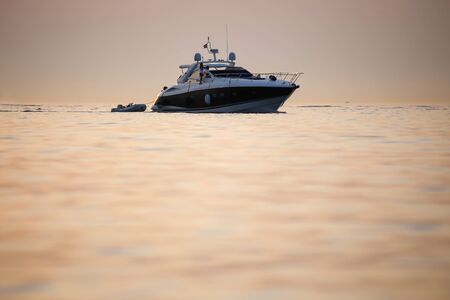 ROVINJ CROATIA  AUGUST 3 : A boat pulling a dinghy sailing in the Adriatic sea at sunset on August 3rd2013 in Rovinj Croatia.のeditorial素材