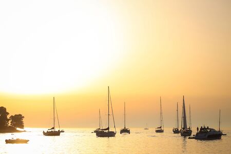 A group of sailboats anchored near the coast in the Adriatic sea at sunset in Rovinj, Croatia.