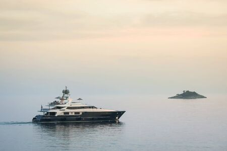 ROVINJ, CROATIA - JUNE 19 : A yacht sailing in the Adriatic sea next to a small island at sunset on June 19th, 2012 in Rovinj, Croatia.のeditorial素材