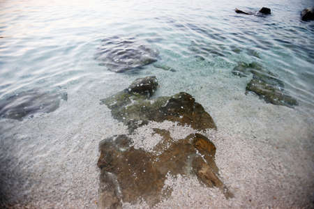 A high angle view of the sea water surface on the beach at sunset.