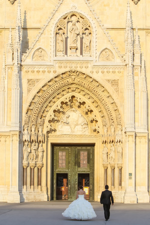 A rear view of newlyweds walking toward the entrance of the Cathedral in Zagreb, Croatia.の写真素材