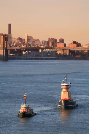 NEW YORK CITY, USA - APRIL 30 : A Meredith C. Reinauer tugboat and a Franklin Reinauer tugboat sailing in the East River with a view of the Brooklyn Bridge on April 30, 2006 in New York City, USA.のeditorial素材