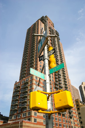 NEW YORK CITY, USA - MARCH 17 : A low angle view of a skyscraper and a lamp post with street signs in intesection of 42nd street and 11th Avenue in Midtown Manhattan on March 17th, 2005 in New York City, USA.のeditorial素材