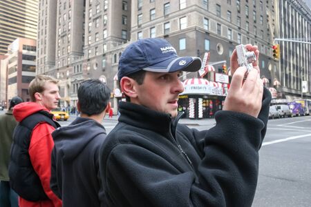 NEW YORK CITY, USA - MARCH 17 : A side view of a tourist standing on the sidewalk and photographing the streets of Midtown Manhattan on March 17th, 2005 in New York City, USA.のeditorial素材