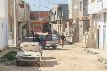 KAIROUAN, TUNISIA - SEPTEMBER 16, 2012 : People walking in a typical dusty and dirty street full of garbage in Kairouan, Tunisia.のeditorial素材