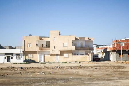 KAIROUAN, TUNISIA - SEPTEMBER 16, 2012 : Residential buildings and typical dusty and dirty street full of garbage in Kairouan, Tunisia.のeditorial素材