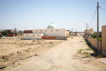 JILMAH, TUNISIA - Typical dusty street with people passing by in Jilmah, Tunisia. Jilmah is one of tunisian towns along the road to the Sahara Desert.の写真素材