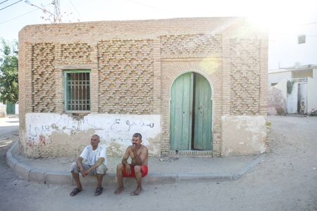 TOZEUR, TUNISIA - SEPTEMBER 16, 2012 : Two tunisian men sitting on the pavement in front of the house in Tozeur, Tunisia.のeditorial素材