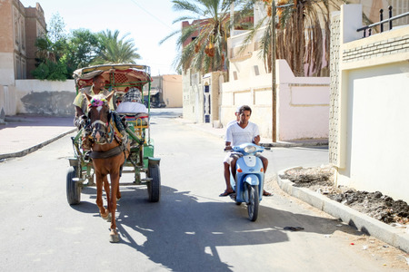 TUNIS, TUNISIA - SEPTEMBER 16, 2012 : A carriage with tourists and a motorcycle driving thru the streets of Tozeur, Tunisia.のeditorial素材