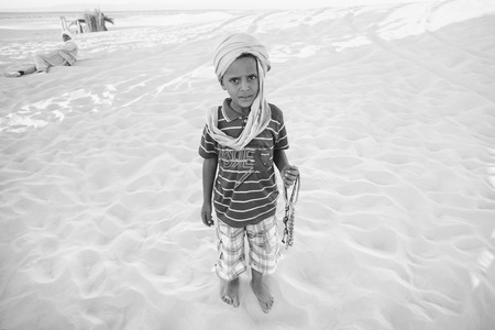 SAHARA, TUNISIA - SEPTEMBER 16, 2012 : Tunisian boy waiting for tourists so that he could sell souvenirs at a tourist stop in Ong Jemel, Tozeur, Tunisia.のeditorial素材