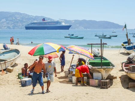 ACAPULCO, MEXICO - MARCH 11, 2006 : People selling fresh fish on the beach with Queen Mary 2 cruise ship in the background in Acapulco, Mexico.のeditorial素材