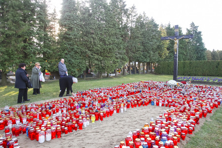 VELIKA GORICA, CROATIA - NOVEMBER 1, 2016 : People praying in front of the cross with a large group of lampions lined up on the ground at cemetery on All Saints day in Velika Gorica, Croatia.のeditorial素材