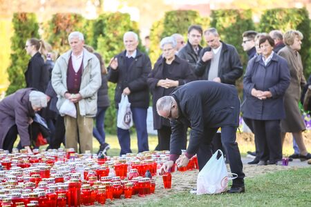 VELIKA GORICA, CROATIA - NOVEMBER 1, 2016 : People praying and lighting candles in front of a large...