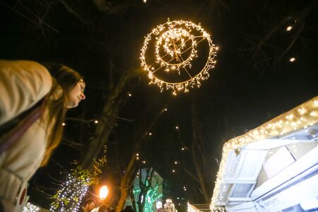 ZAGREB, CROATIA - DECEMBER 1th, 2016: Advent time in city center of Zagreb, Croatia. Woman sightseeing the food and souvenir stands at decorated Stross promenade in the upper old town Gradec.のeditorial素材