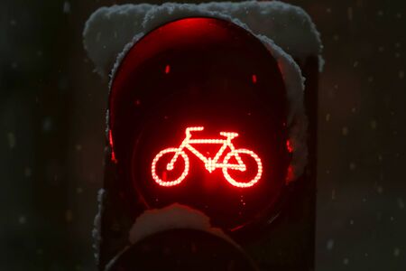A close up of scoreboad showing red light for bicycles during snowfall.の写真素材