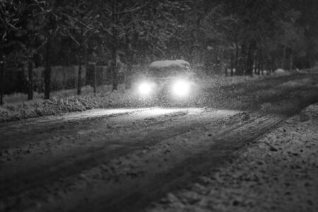 A car driving on the road in the aggravated traffic due to strong snowfall.の写真素材