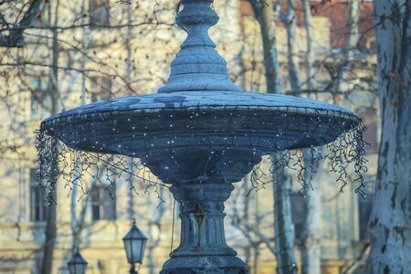 The top of a stone water fountain decorated with illuminating ornaments at Christmas time in Zrinjevac park in Zagreb, Croatia.の写真素材