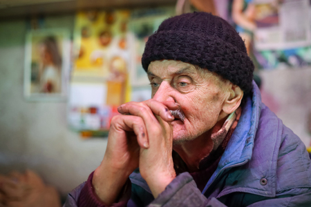 A close up of an old man holding hands together and looking away.の写真素材