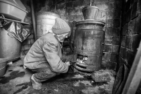 An older man making homemade brandy in the boilers in his shed.の写真素材
