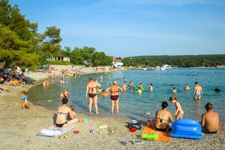 NJIVICE, CROATIA - JUNE 24, 2017 : People bathing and sunbathing on sea beach in Njivice, Croatia.のeditorial素材