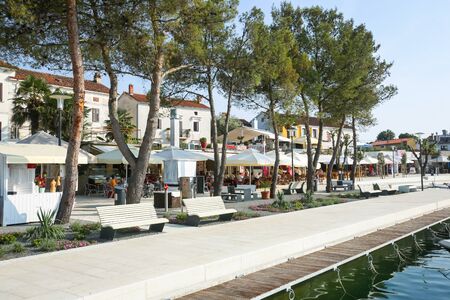 NJIVICE, CROATIA - JUNE 24, 2017 : People walking on waterfront with modern benches and restaurants in Njivice, island of Krk, Croatia.のeditorial素材