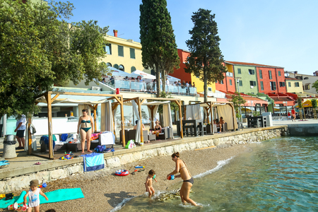 NJIVICE, CROATIA - JUNE 24, 2017 : People on the seafront beach with colorful architecture of hotel Jadran in the background in Njivice, island Krk, Croatia.のeditorial素材