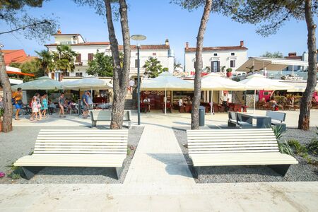 NJIVICE, CROATIA - JUNE 24, 2017 : People walking on waterfront with modern benches and restaurants in Njivice, island of Krk, Croatia.のeditorial素材