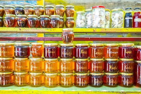 Homemade food products, honey of several plants, lavender, rosemary, pomegranate, sage and mandarin and jam of several types of fruit, figs, mandarin and plum displayed at a food stand.の写真素材