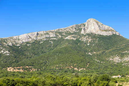A view of rural landscape with rocky mountains under clear blue sky.の写真素材