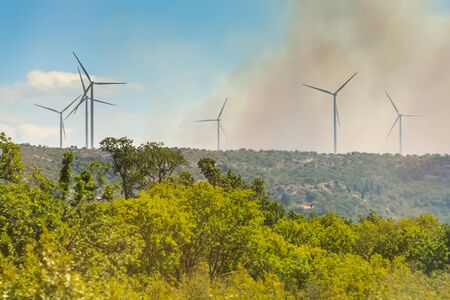 Windmills in a smoke cloud from a forest fire in Dalmatia, Croatia.の写真素材