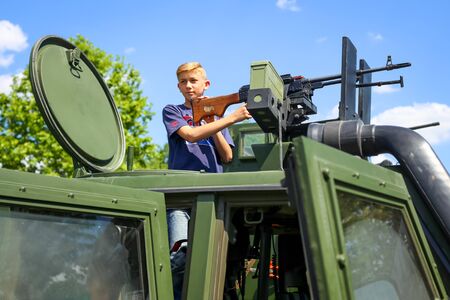 ZAGREB, CROATIA - MAY 28, 2017 : A boy poses with the machine gun on the Mrap m-atv vehicle on the 26th anniversary of the formation of the Croatian Armed Forces on Lake Jarun in Zagreb, Croatia.のeditorial素材