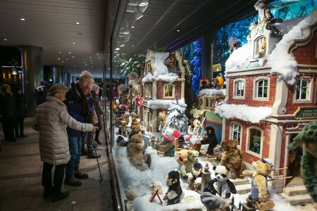 MUNICH, GERMANY - DECEMBER 11, 2017 : People sightseeing the shop window of Galeria Kaufhof ornated with toys in winter style at night in Munich, Germany.のeditorial素材