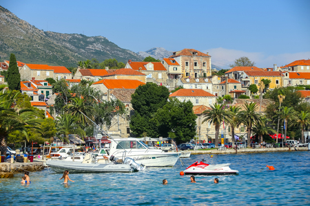 CAVTAT, CROATIA - JULY 20, 2017 : A view of boats anchored in front of seaside with people swimming in the sea in Cavtat, Croatia.のeditorial素材